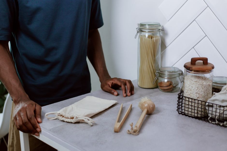 A modern kitchen counter with glass jars, utensils, and a person in a navy shirt.